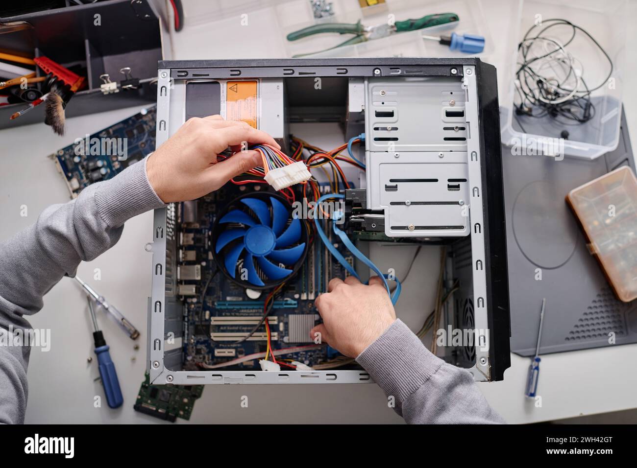 Hands of unrecognizable male repairman arranging wires in disassembled system unit of computer Stock Photo