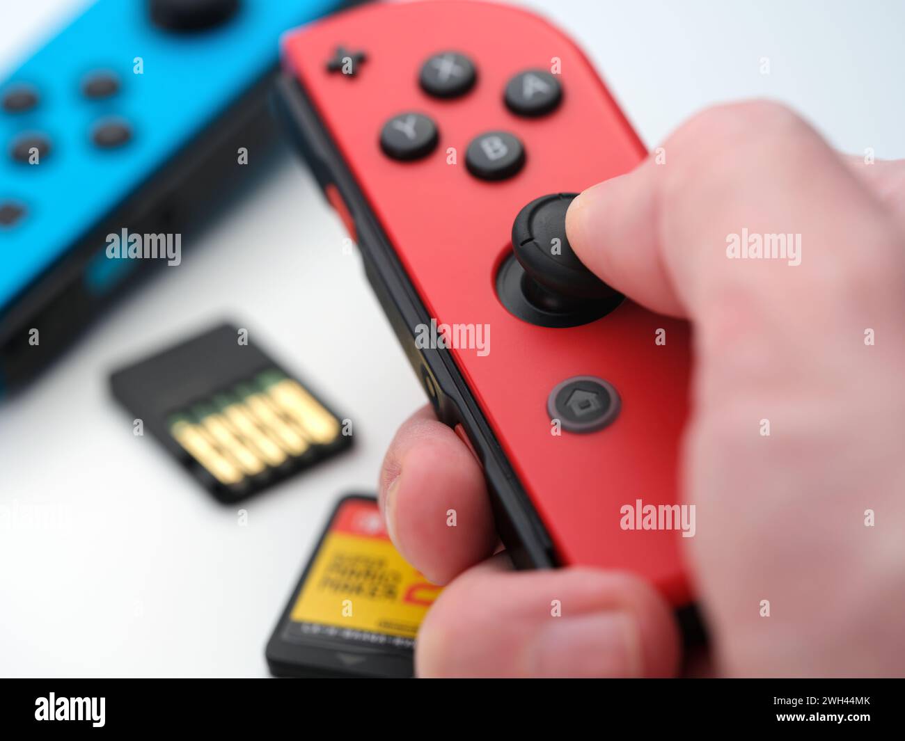 Tambov, Russian Federation - February 03, 2024 A man holding a red Nintendo Switch joy con above two Nintendo Switch cartridges and a blue joy con. Cl Stock Photo