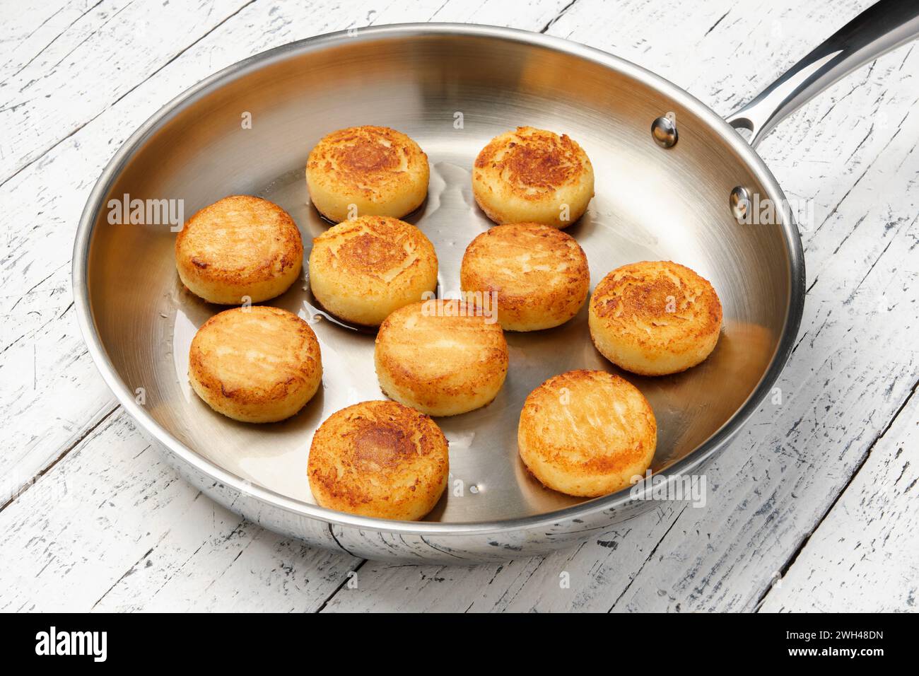 Cottage cheese pancakes. Syrniki in a frying pan. Cheesecakes. Stock Photo