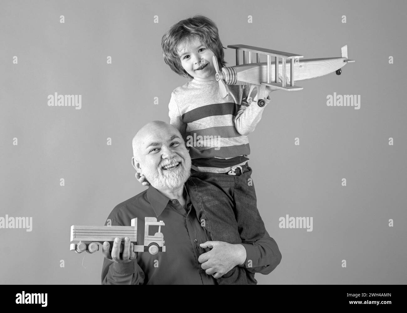 Old grandfather and young child grandson piggyback with toy plane and