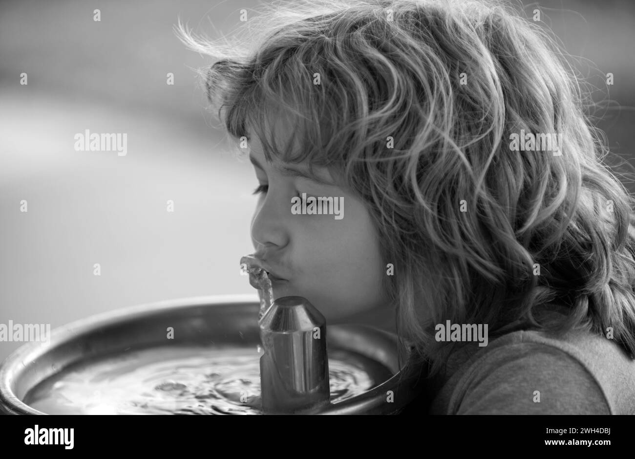Kid drinking water from outdoor water fountain outdoor. Thirsty child. Stock Photo