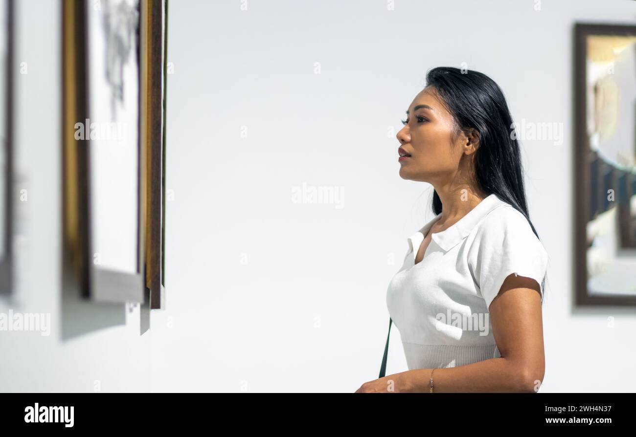 A young woman looks at paintings at an exhibition Stock Photo - Alamy