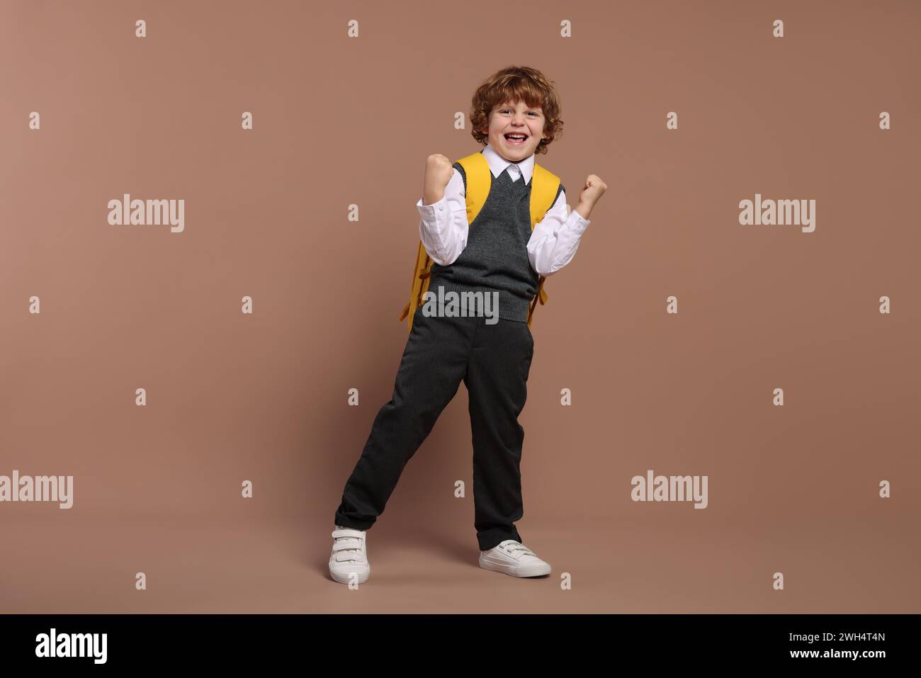Emotional schoolboy with backpack on brown background Stock Photo - Alamy