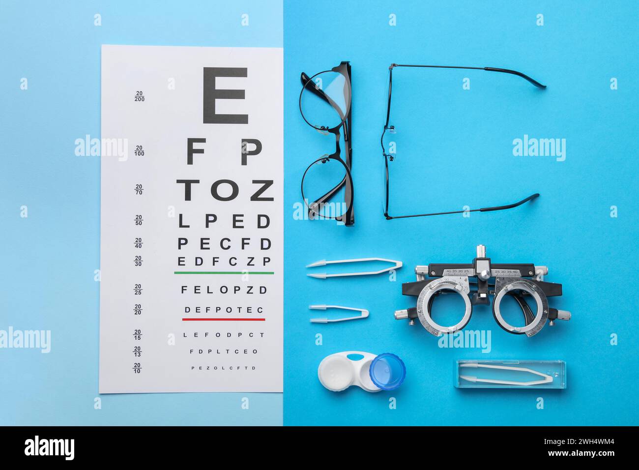 Lay Vision Flat lay composition with vision test chart and glasses on light blue ...