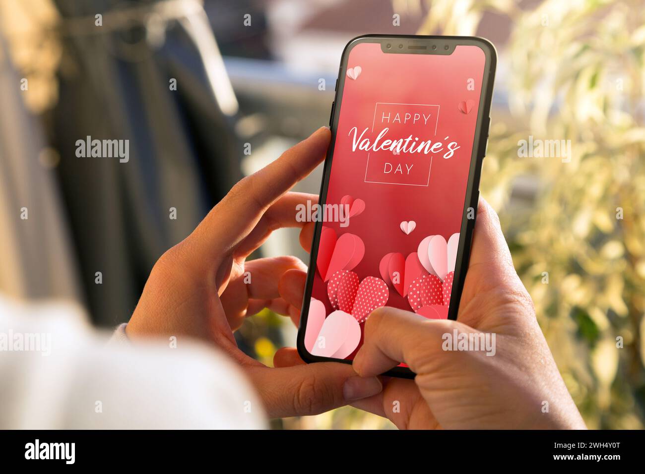 Woman showing a digital Valentine's Day greeting card in the mobile phone screen. Stock Photo