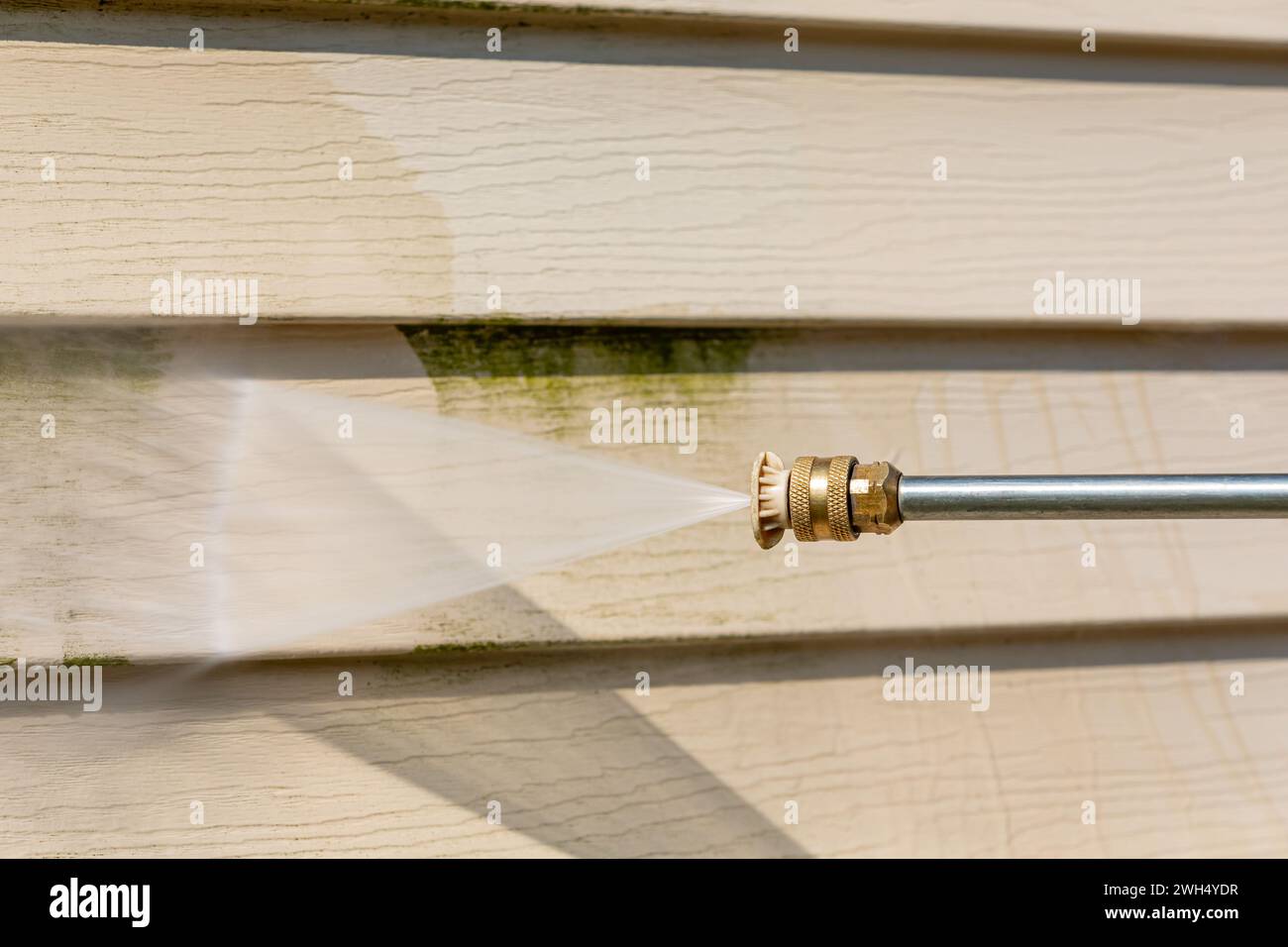 Cleaning algae, mold and mildew from vinyl siding of house with pressure washer. Home repair, maintenance and exterior cleaning concept. Stock Photo