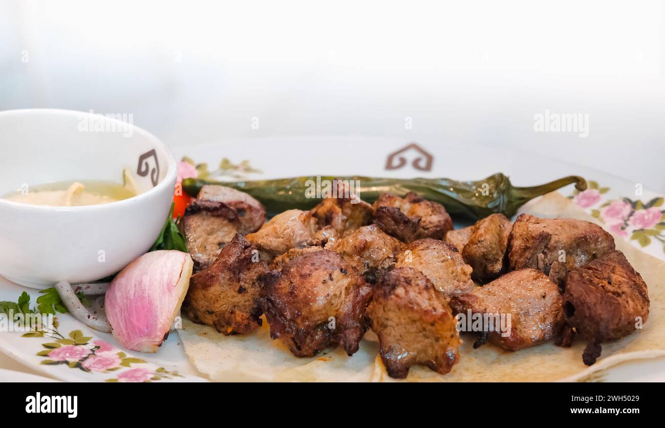 Arabic beef kebab with dipping sauce and onion on white background
