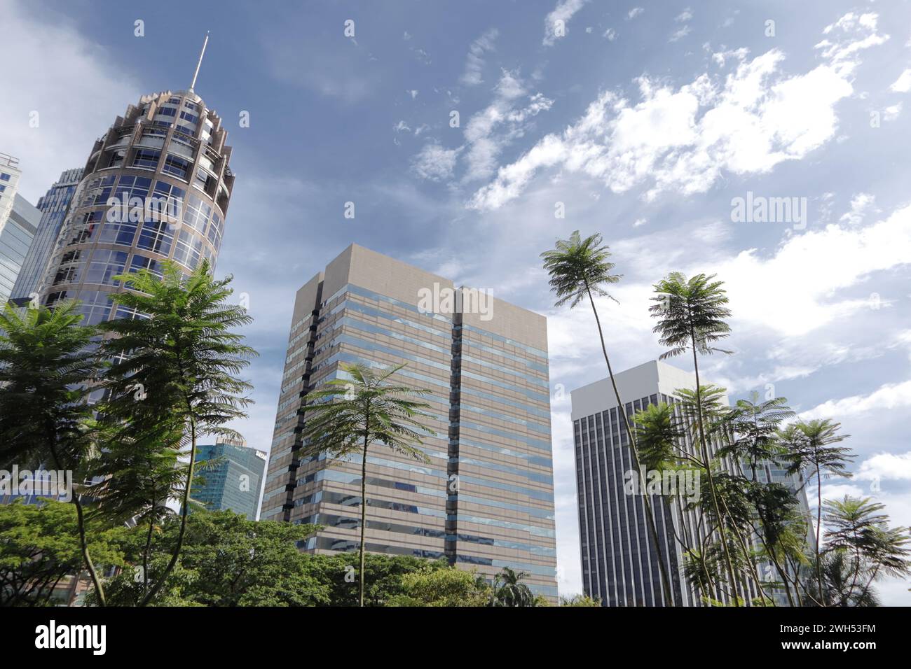 A landscape of three buildings with some trees in front. Under cloudy
