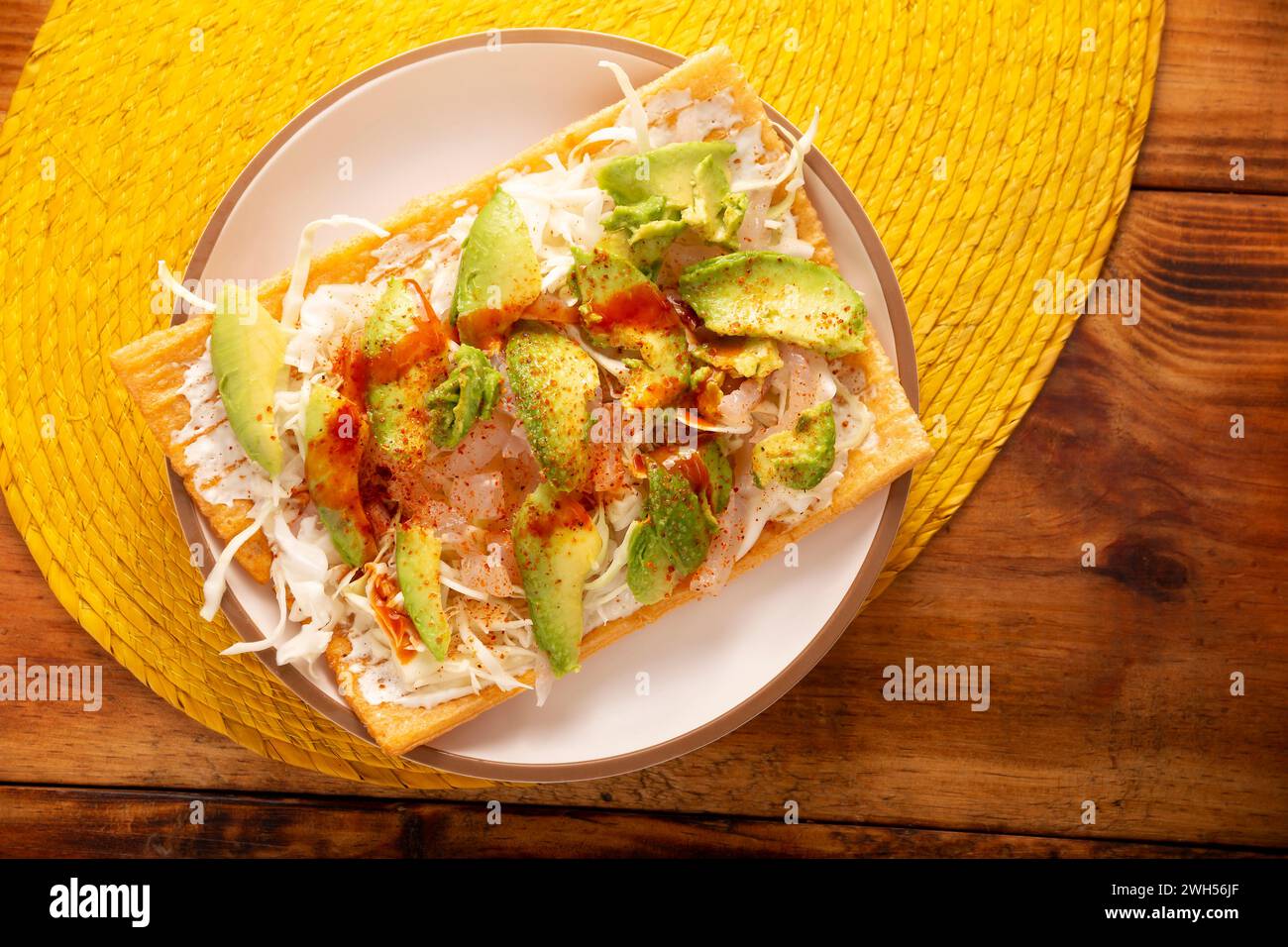 Fried wheat flour toast with pickled pork skin, sour cream and vegetables with hot sauce, in Mexico is called Chicharron preparado, traditional street Stock Photo