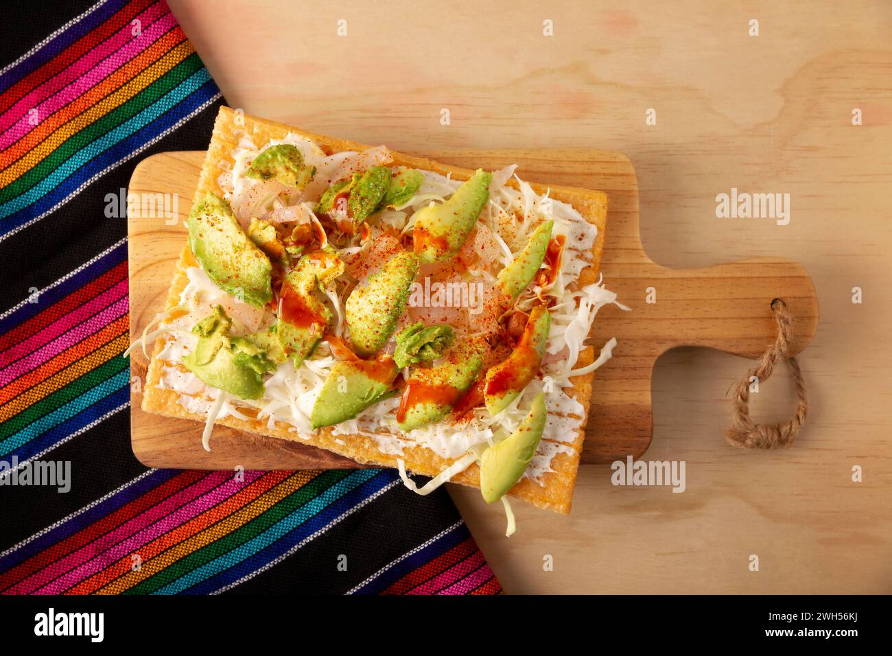 Fried wheat flour toast with pickled pork skin, sour cream and vegetables with hot sauce, in Mexico is called Chicharron preparado, traditional street Stock Photo