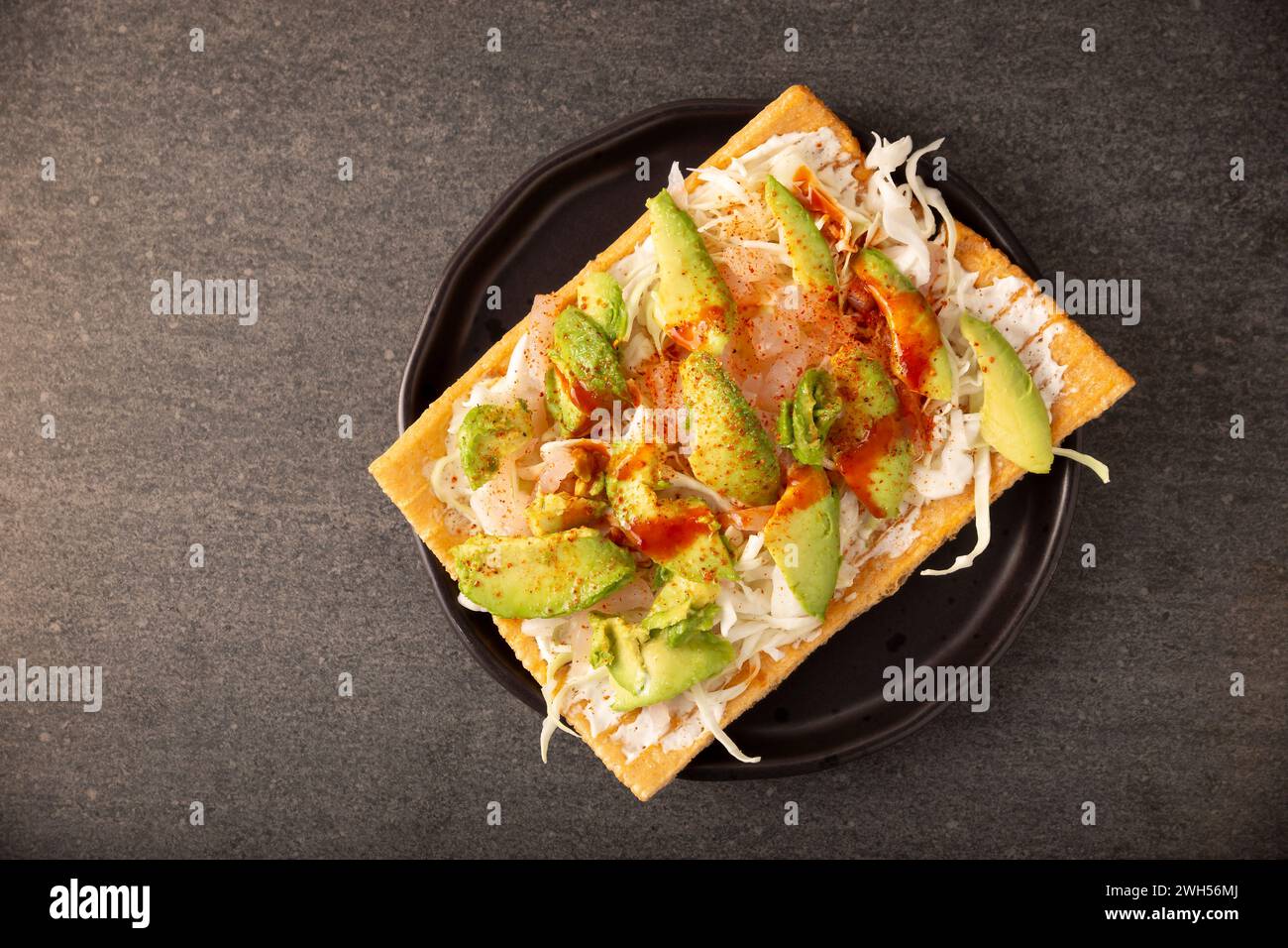 Fried wheat flour toast with pickled pork skin, sour cream and vegetables with hot sauce, in Mexico is called Chicharron preparado, traditional street Stock Photo