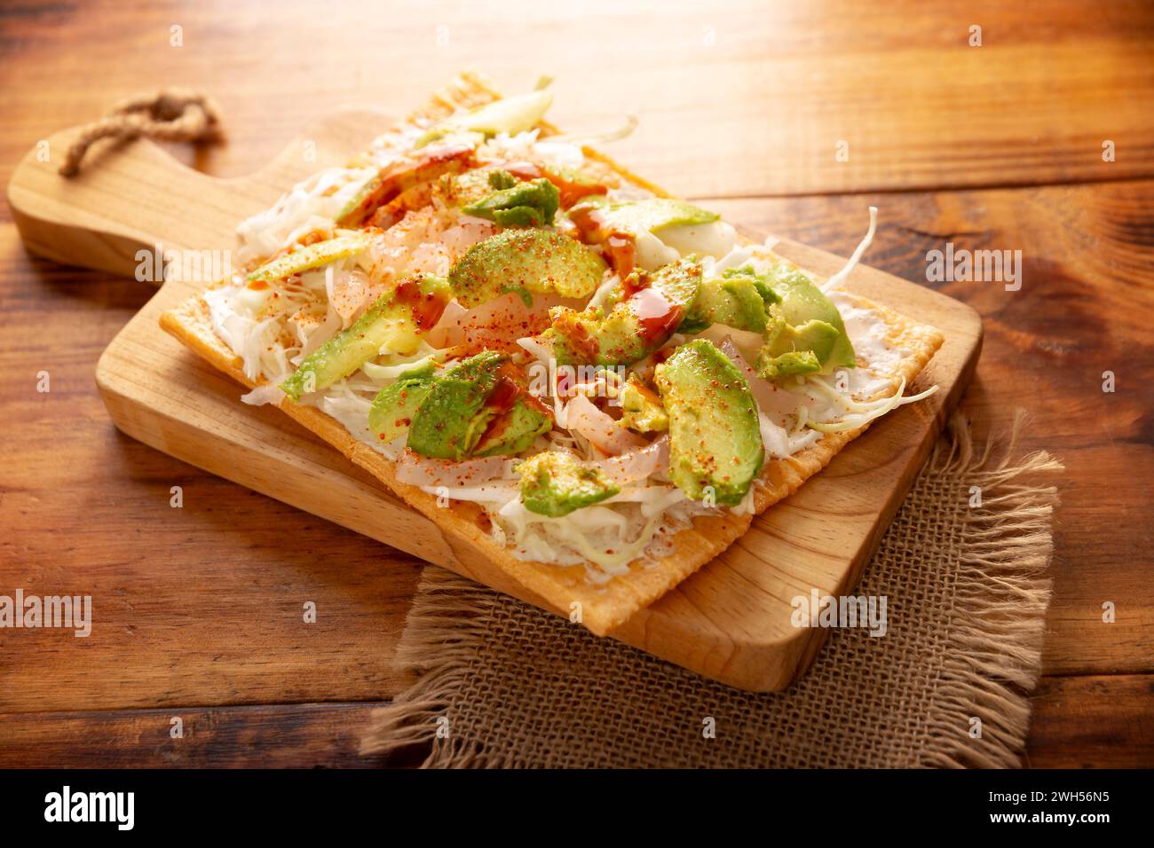 Fried wheat flour toast with pickled pork skin, sour cream and vegetables with hot sauce, in Mexico is called Chicharron preparado, traditional street Stock Photo