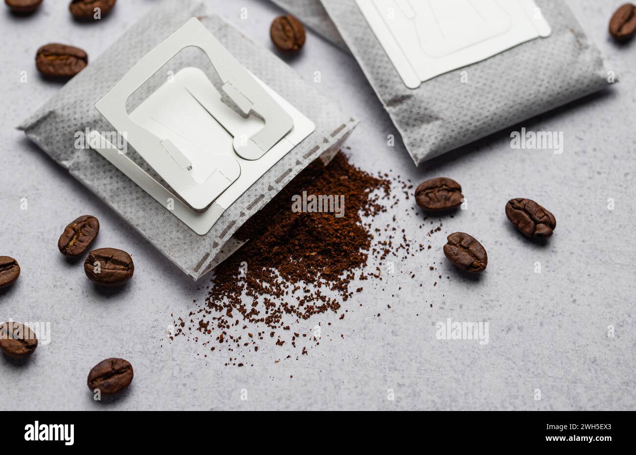 Drip coffee paper bags with coffee beans on a grey concrete background Stock Photo