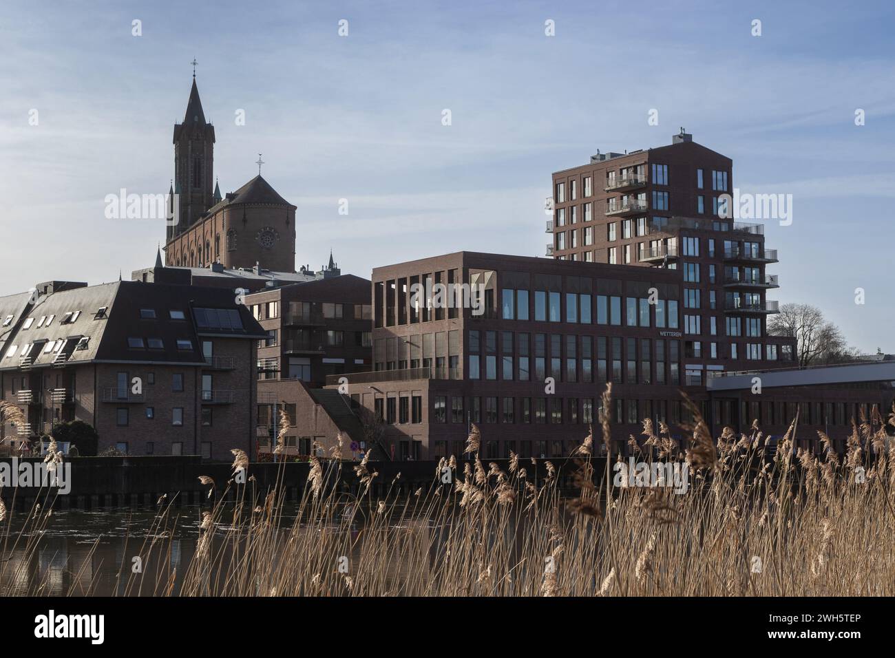 Wetteren city skyline with St Gertrudes church and the red hill buildings, in East Flanders, Belgium. View accross the Schelde river. Copy space above Stock Photo