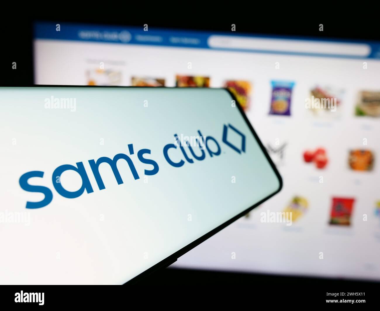 Cellphone with logo of American membership-only retail stores company Sam's Club in front of website. Focus on center-left of phone display. Stock Photo