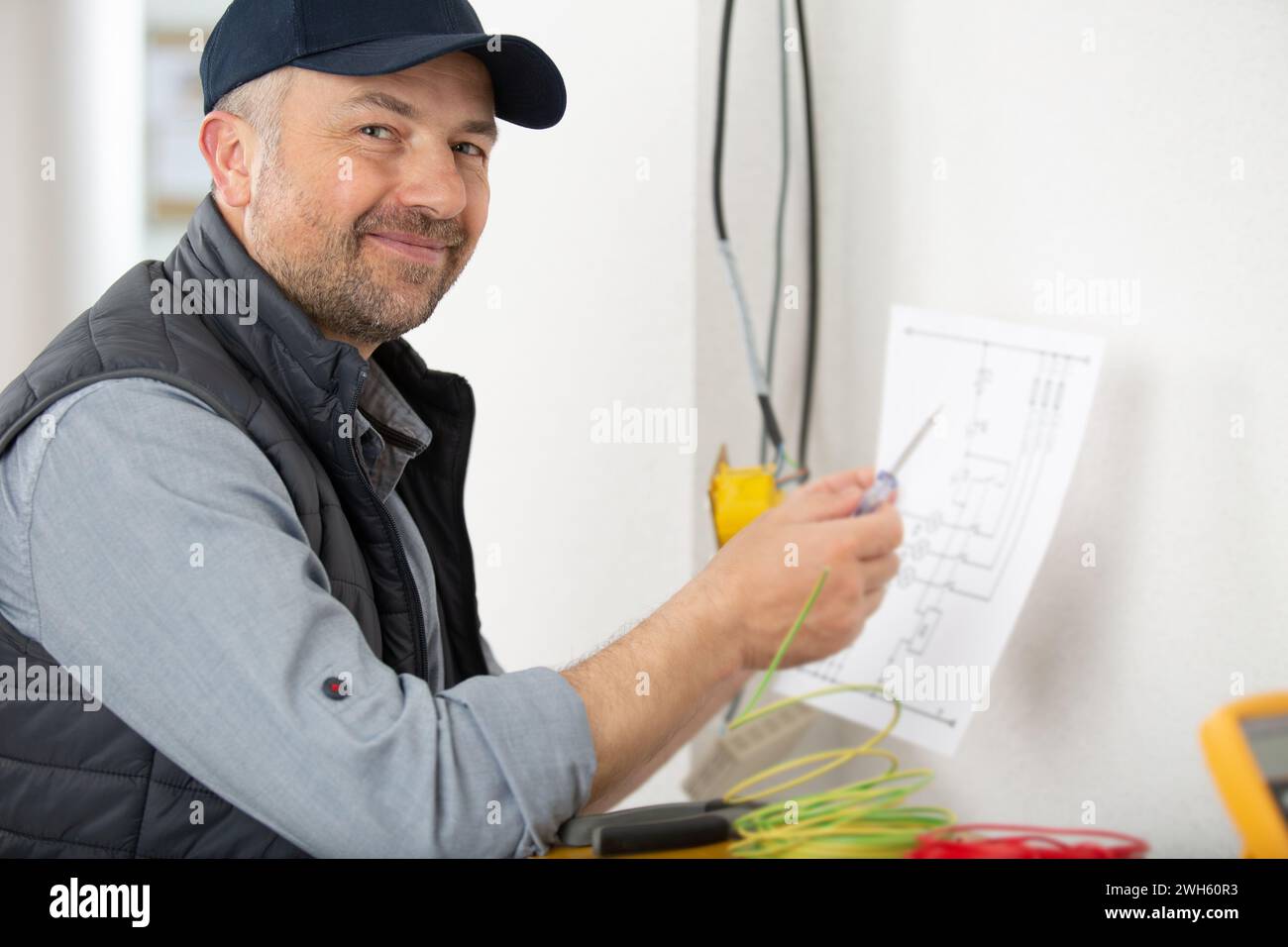 male electrician checking voltage of socket with multimeter in house Stock Photo