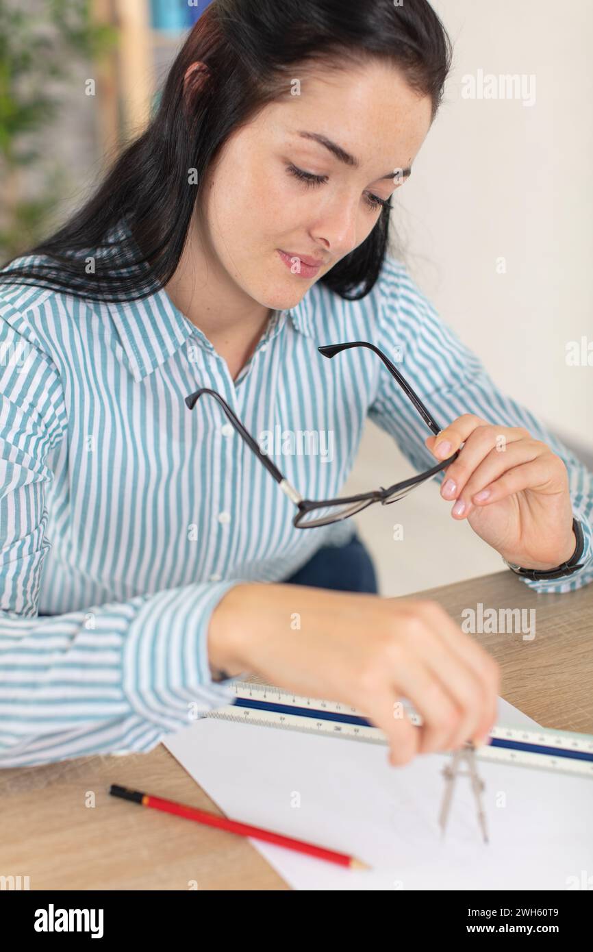 female architect at desk using compass Stock Photo