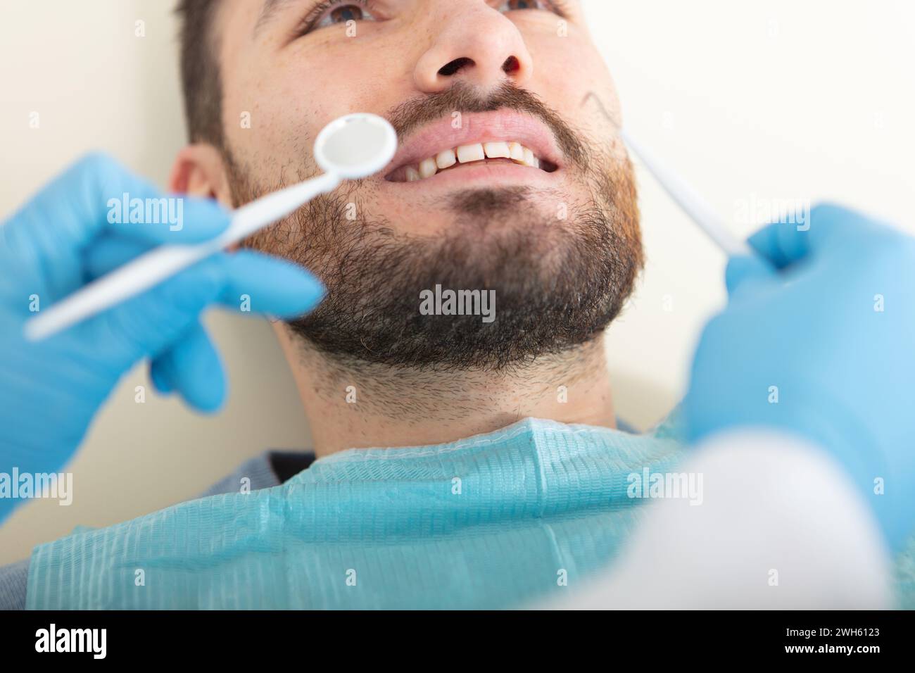 female dentist examining a male patient at clinic Stock Photo