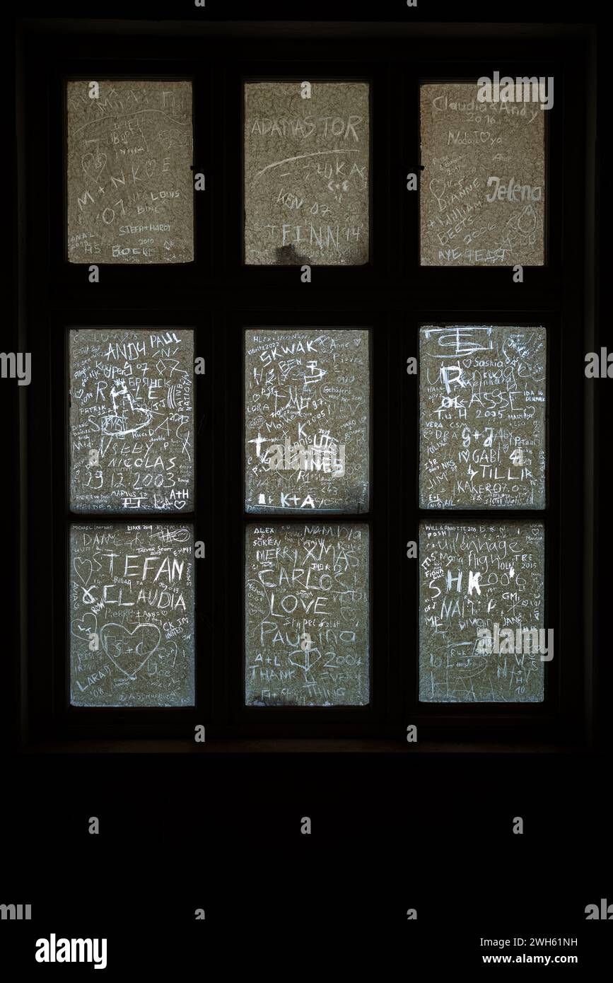 A vertical shot of names and hearts scratched into dirty old window panes Stock Photo