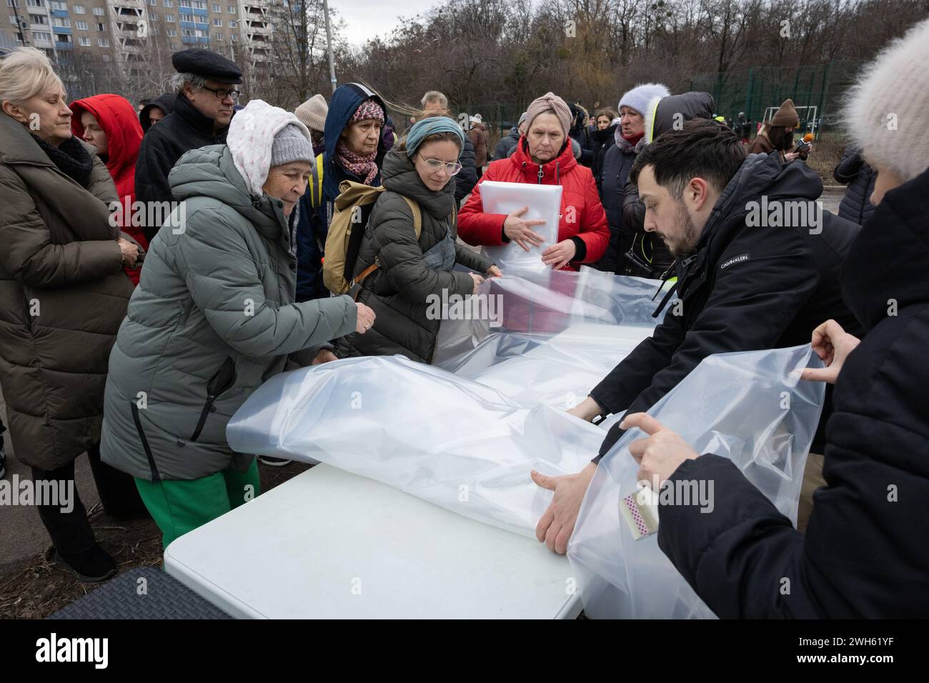 Kyiv, Ukraine. 07th Feb, 2024. Municipal workers distribute plastic film to residents of damaged apartments to cover broken windows in the building damaged by falling debris of a shot-down Russian missile following a missile strike in Kyiv. At least four people were killed and 19 others were injured after a Russian shelling hit Kyiv, according to Ukrainian Emergency Services. (Photo by Oleksii Chumachenko/SOPA Images/Sipa USA) Credit: Sipa USA/Alamy Live News Stock Photo