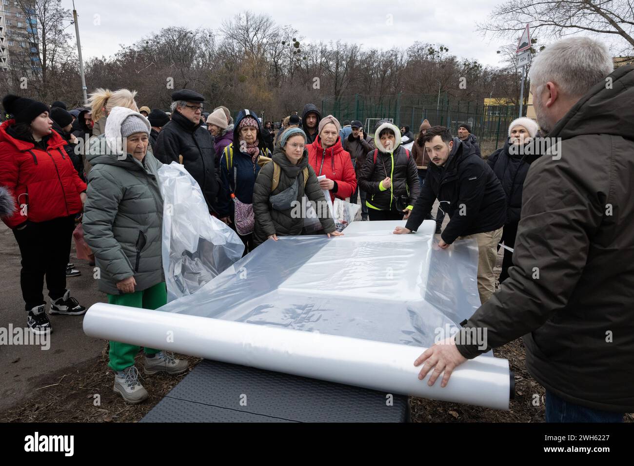 Kyiv, Ukraine. 07th Feb, 2024. Municipal workers distribute plastic film to residents of damaged apartments to cover broken windows in the building damaged by falling debris of a shot-down Russian missile following a missile strike in Kyiv. At least four people were killed and 19 others were injured after a Russian shelling hit Kyiv, according to Ukrainian Emergency Services. (Photo by Oleksii Chumachenko/SOPA Images/Sipa USA) Credit: Sipa USA/Alamy Live News Stock Photo