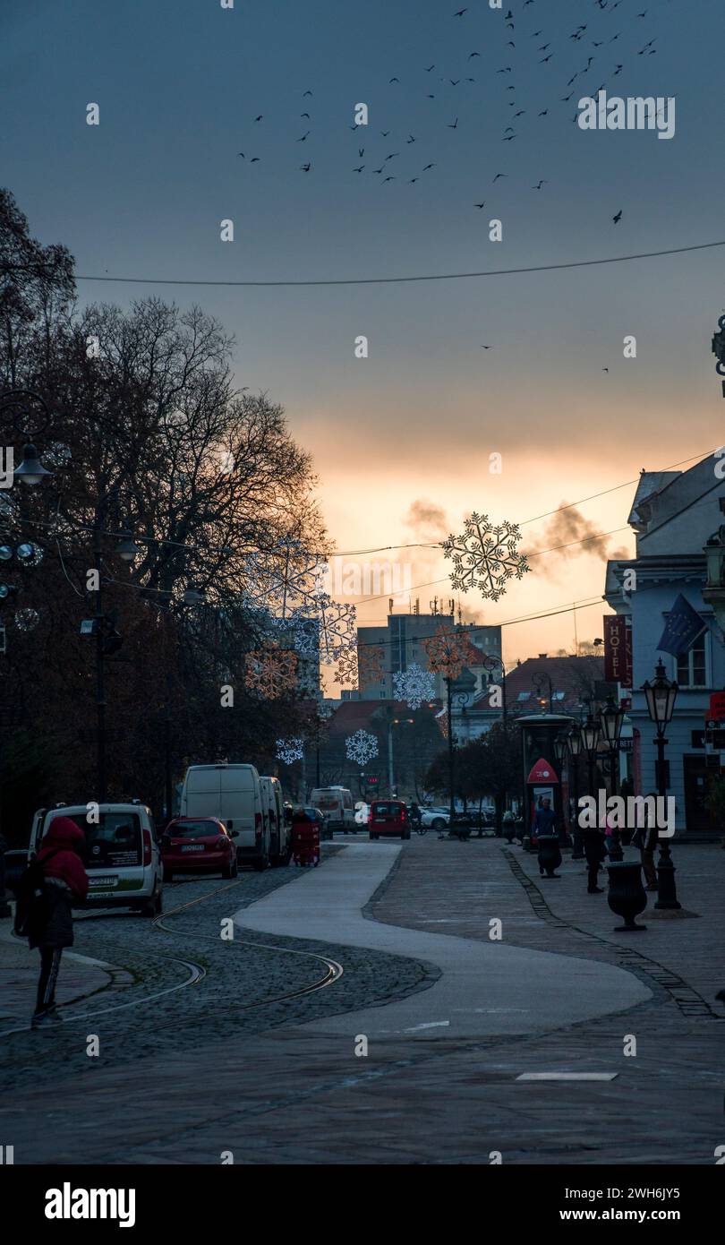 Cars driving down a road alongside buildings Stock Photo