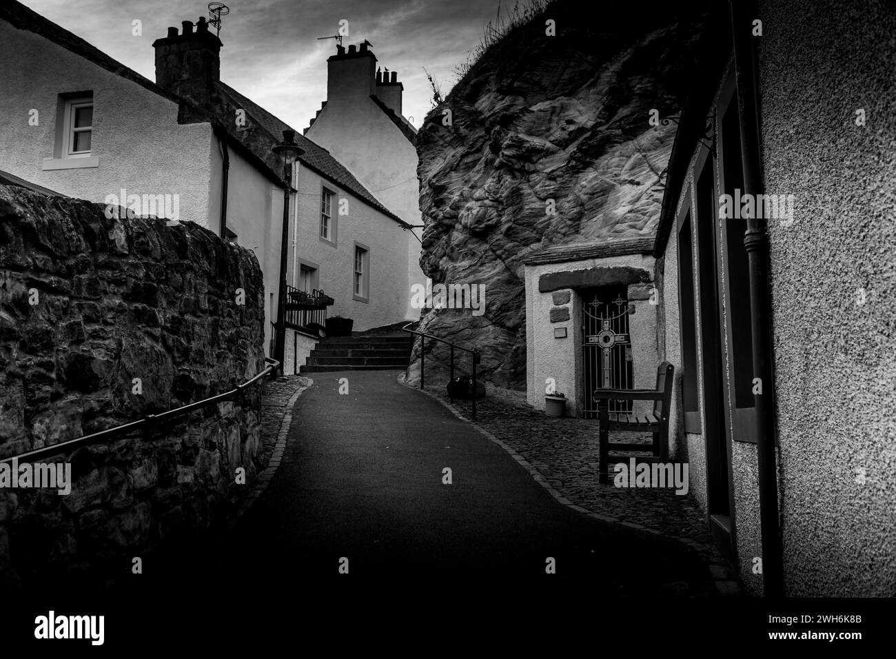 A beautiful stone pathway leading to a small gate at the top of a hill Stock Photo