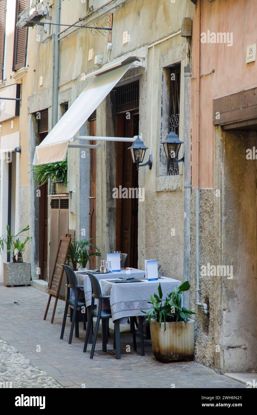 Two small restaurant tables set up for al fresco dining in a street in Riva Del Garda, Italy Stock Photo