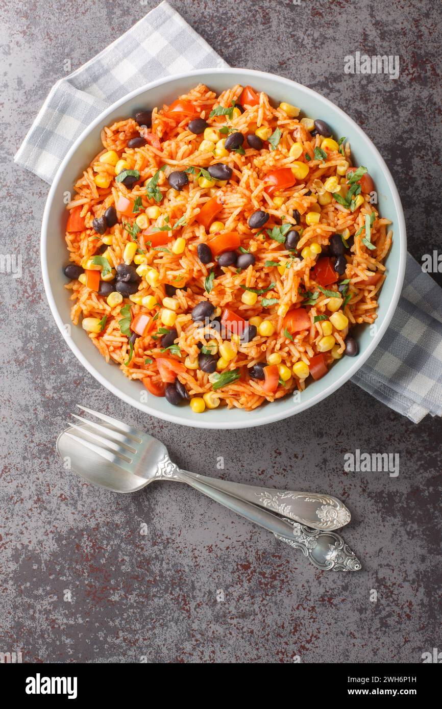 Delicious authentic Mexican tomato rice with black beans, onions and corn close-up in a bowl on the table. Vertical top view from above Stock Photo