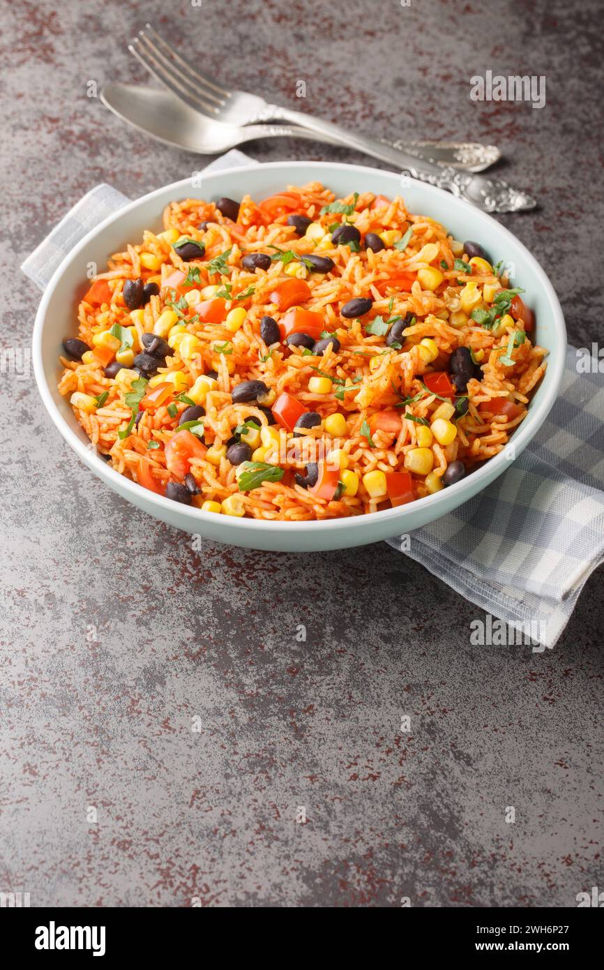 Delicious authentic Mexican tomato rice with black beans, onions and corn close-up in a bowl on the table. Vertical Stock Photo
