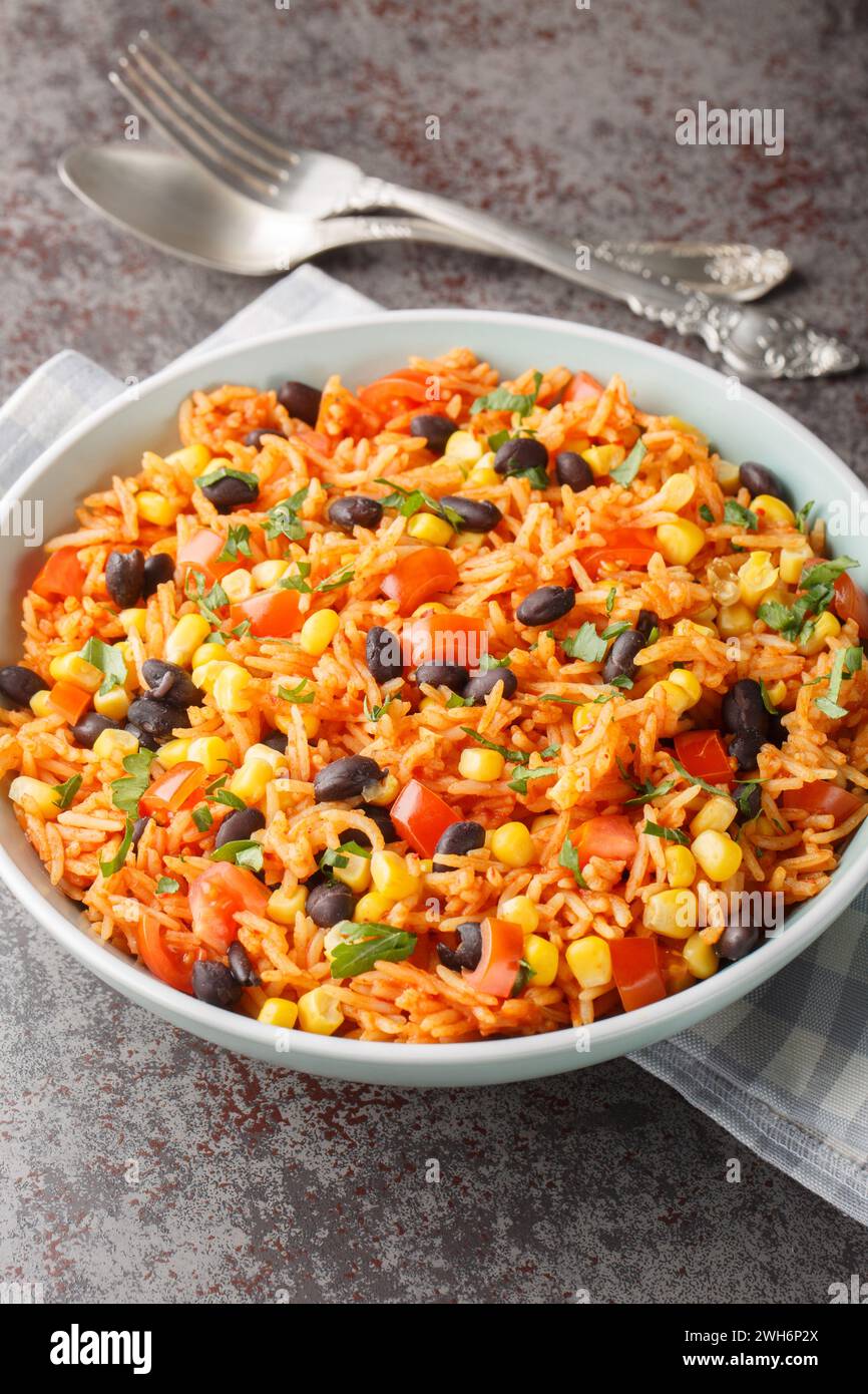 Mexican tomato rice with black beans, onions and corn close-up in a bowl on the table. Vertical Stock Photo