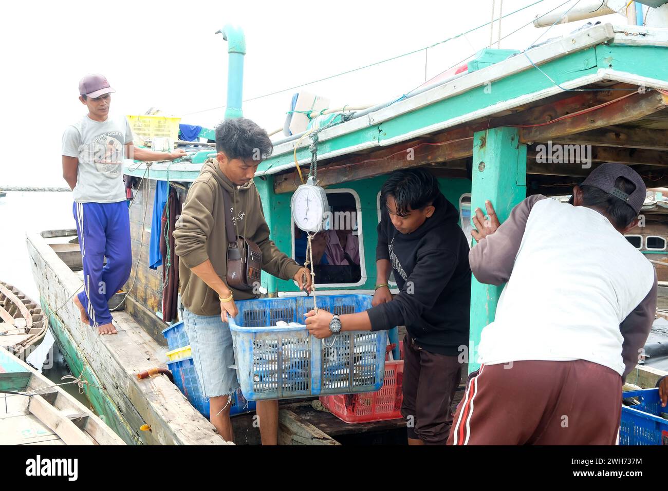 Lampung, Indonesia, 07 October 2022: Fishermen or crew weigh fish in a basket that has just been caught on a boat Stock Photo