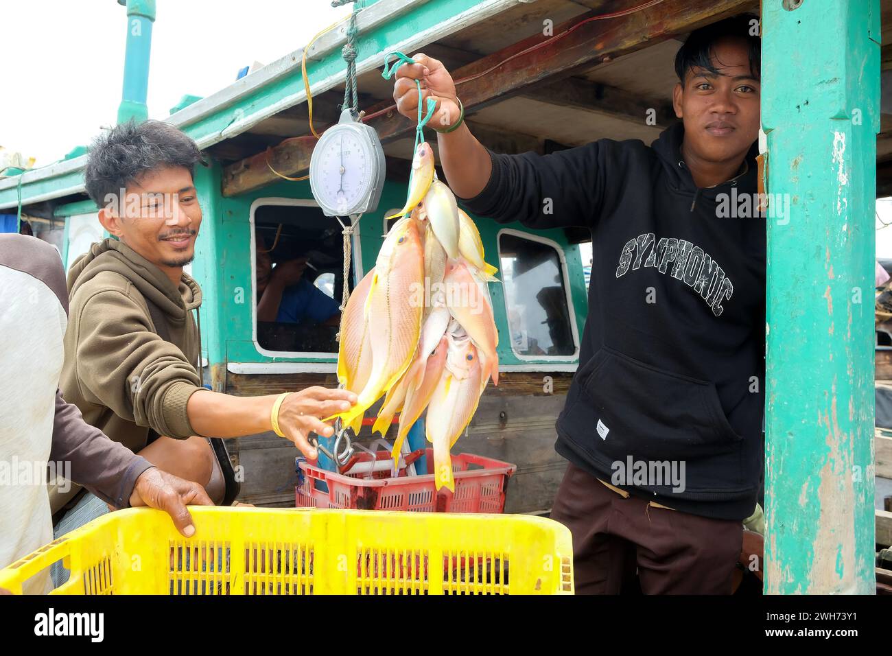 Lampung, Indonesia, 07 October 2022: Focusing on fish, an Indonesian man holds a fish hanger on a fishing boat in Lampung, Indonesia. Stock Photo