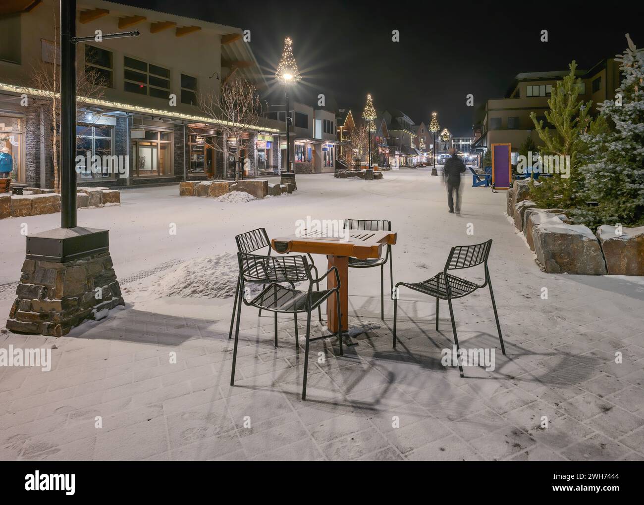 Table and chairs with a blurred person on Bear Street in Banff, Alberta, Canada Stock Photo