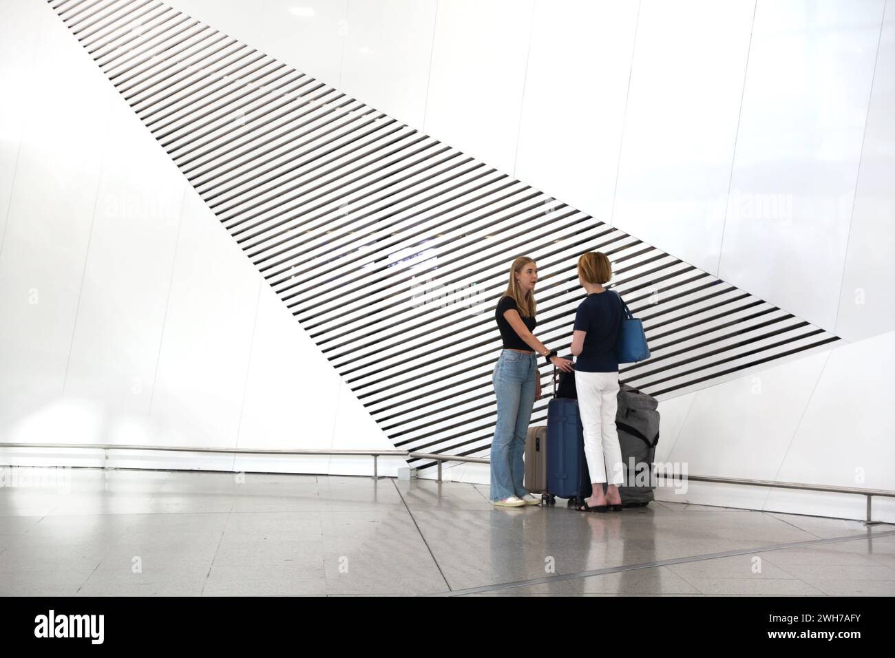 Athens Greece Athens International Airport (AIA) Eleftherios Venizelos Women With Suitcases Standing next to Artistic Vents in the Wall Stock Photo
