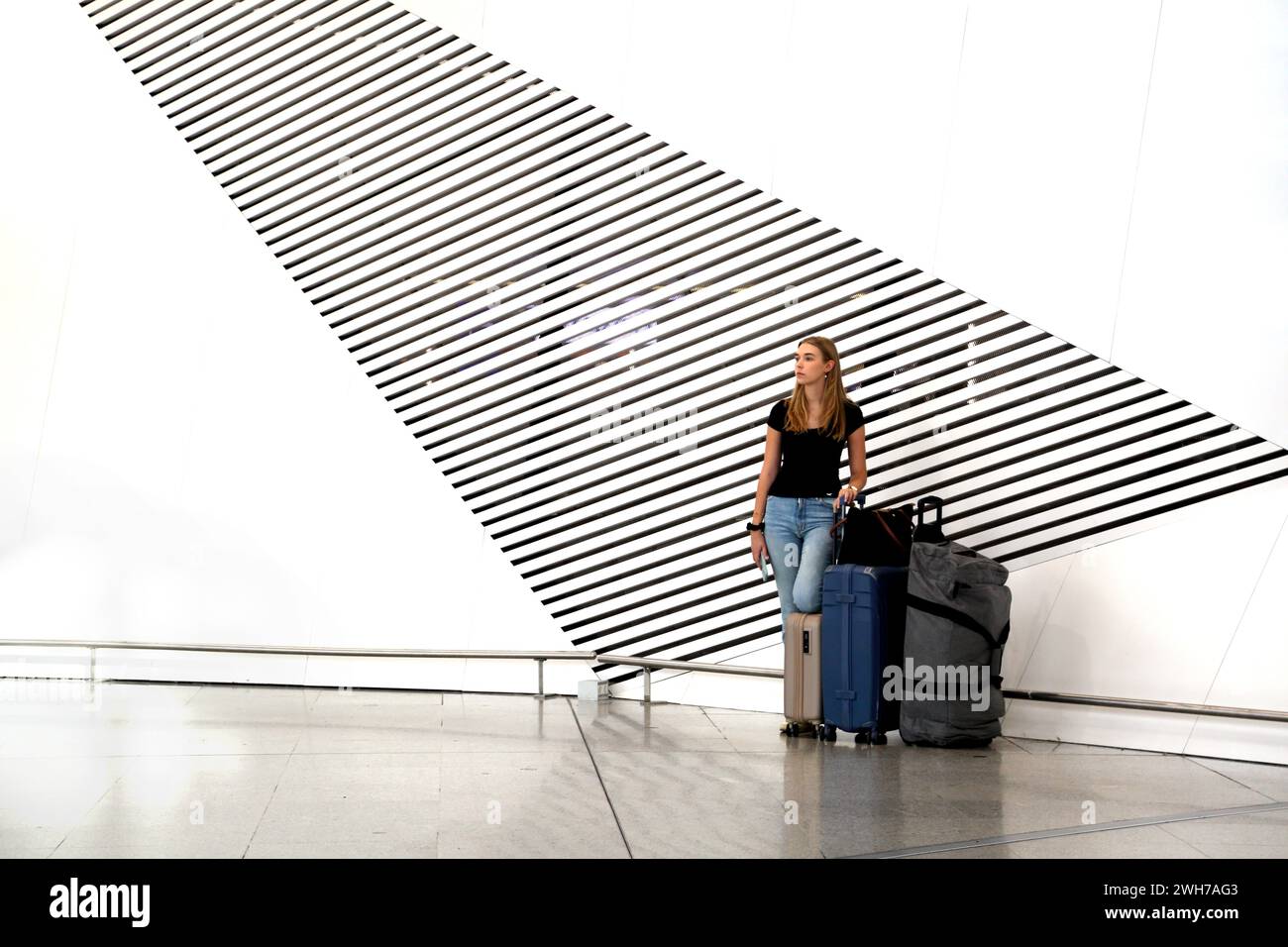 Athens Greece Athens International Airport (AIA) Eleftherios Venizelos Woman With Suitcases Standing next to Artistic Vents in the Wall Stock Photo