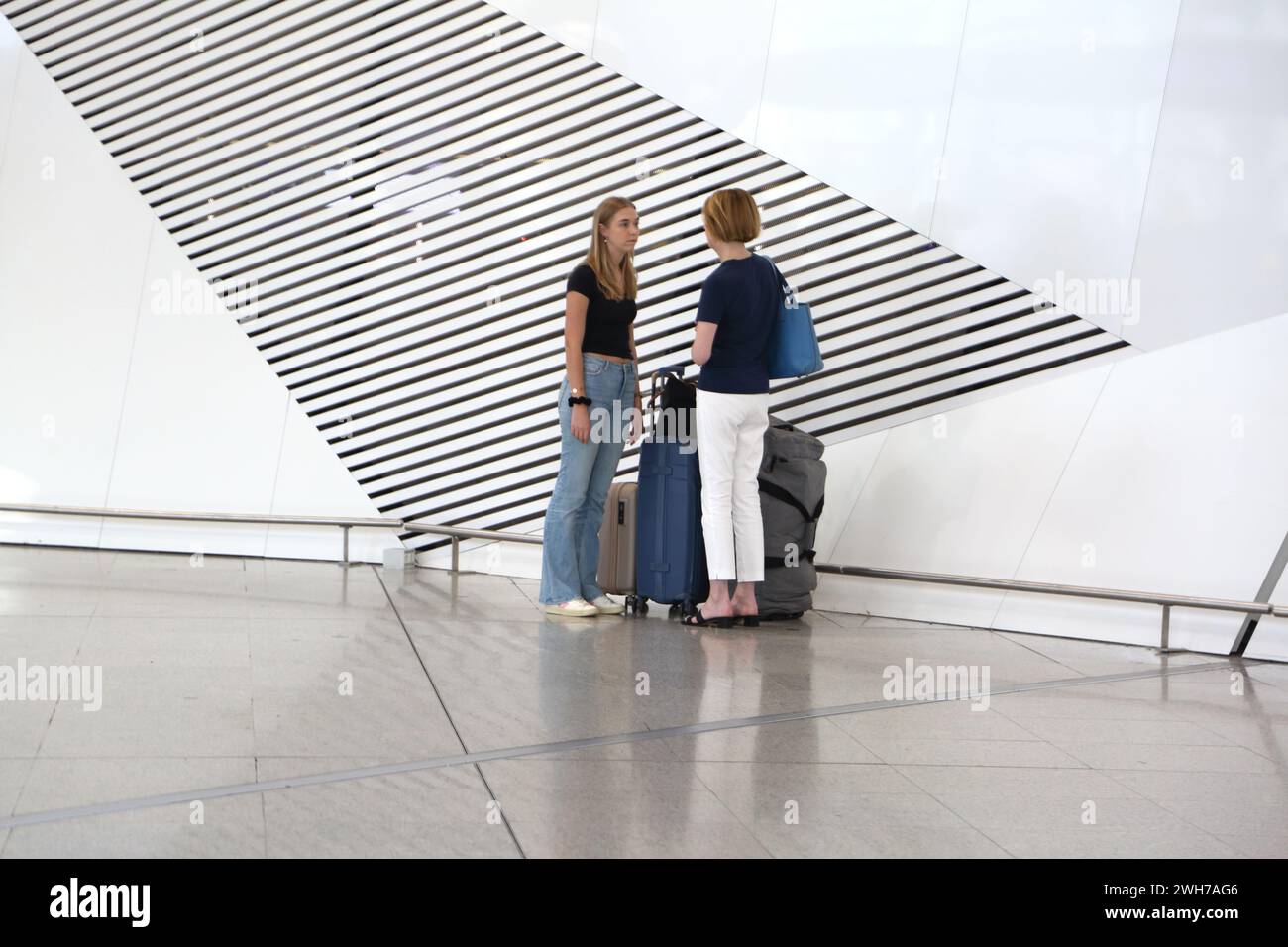 Athens Greece Athens International Airport (AIA) Eleftherios Venizelos Women With Suitcases Standing next to Artistic Vents in the Wall Stock Photo