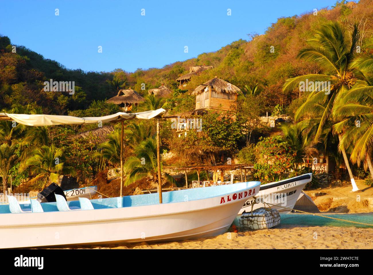 Fishing boats and grass huts fill the beach in the town of Mazunte in southern Mexico. Stock Photo