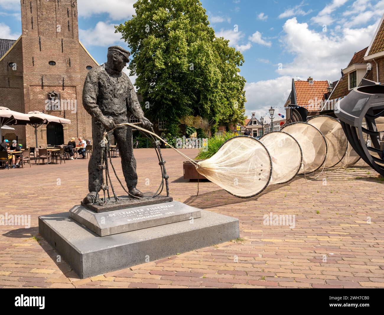 Statue of Lemster Fiskerman, fisherman retrieving his net in front of Reformed Church in Lemmer, Friesland, Netherlands Stock Photo