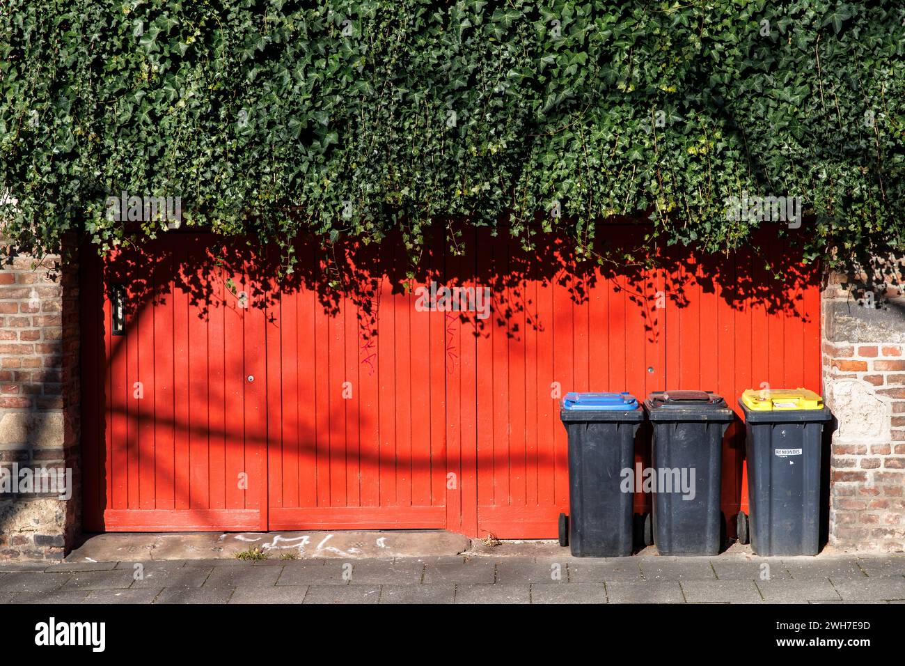 bins in front of a red gate on Gereonswall, waste seperation, Cologne, Germany. Muelleimer stehen vor einem roten Tor am Gereonswall, Muelltrennung, K Stock Photo