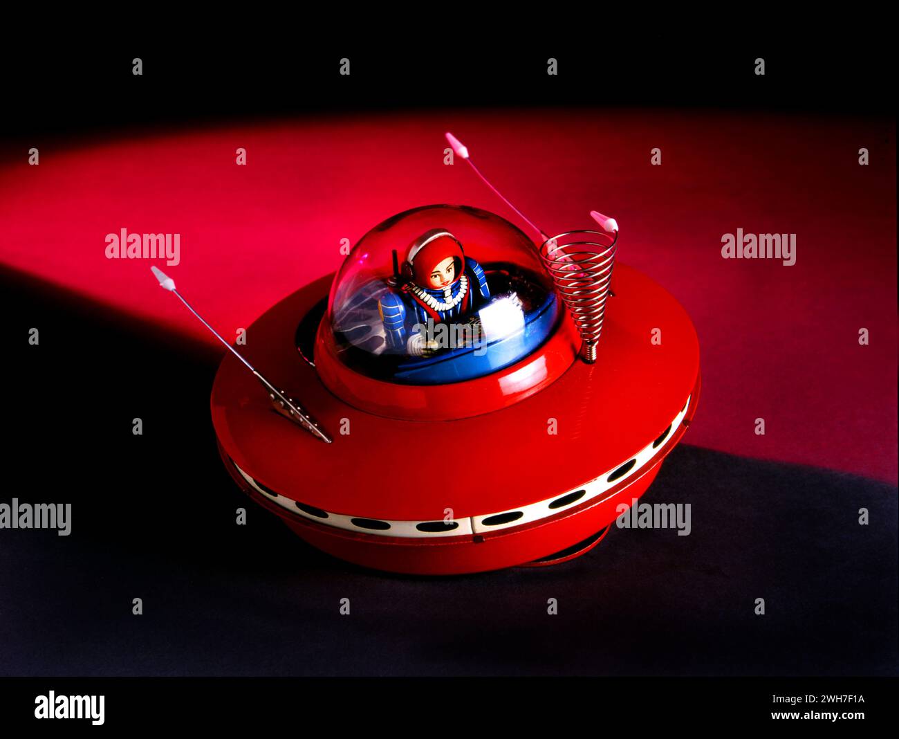 A red metal, vintage, antique flying saucer toy with pilot. Stylized studio photo. Stock Photo
