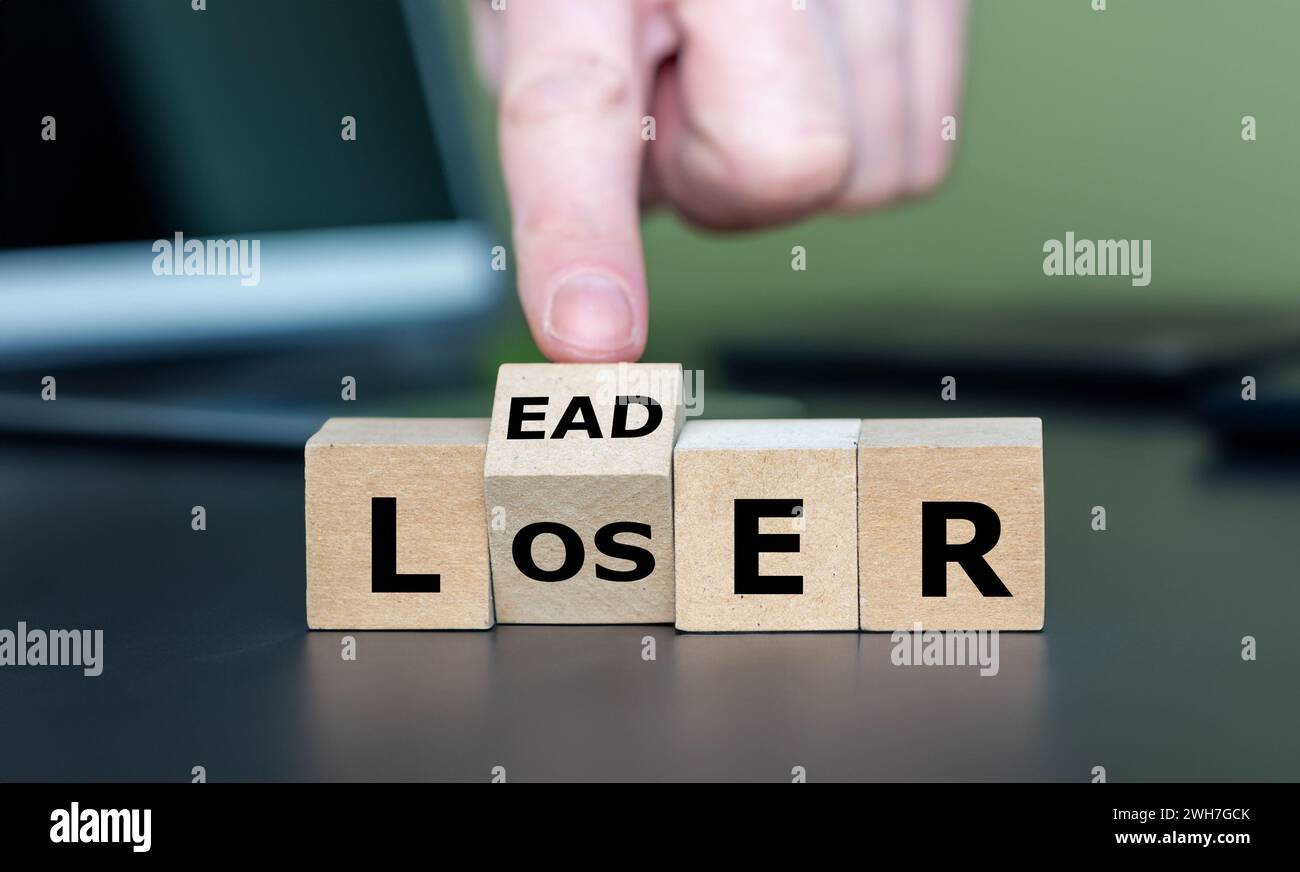Hand turns wooden cube and changes the word loser to leader Stock Photo