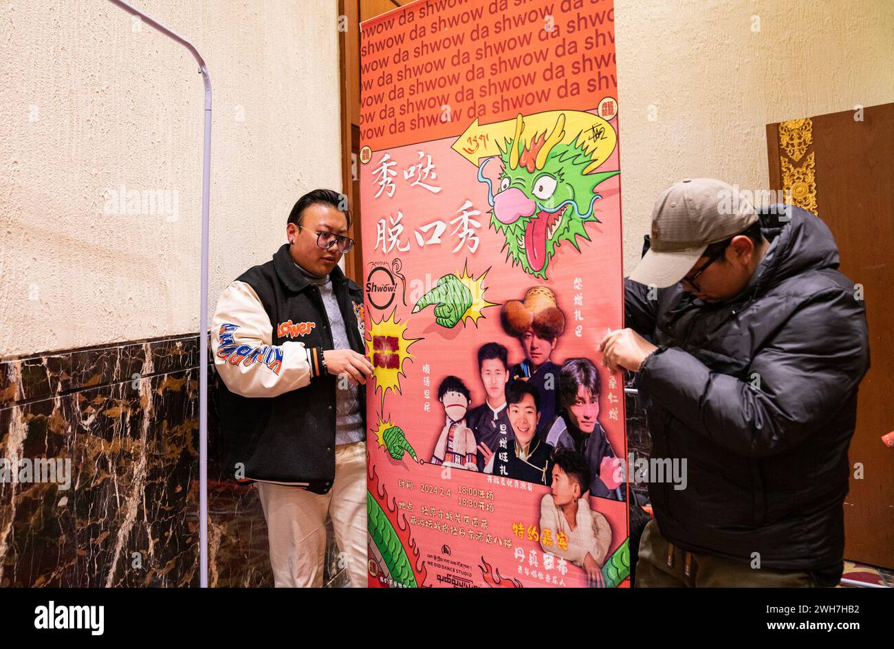 (240208) -- LHASA, Feb. 8, 2024 (Xinhua) -- Team members set up a poster of talk show in Lhasa, southwest China's Xizang Autonomous Region, Feb. 3, 2024. Nyanzin Drakpa, a senior at the Communication University of China, set up a Tibetan-language talk show team in the summer of 2021, hoping to get more people to watch Tibetan language talk shows. On the stage, Nyanzin Drakpa is a witty stand-up comedian. Behind the scenes, he's the backbone of the team. Every time before the show, he and his team members come to the venue in advance to adjust the equipment and rehearse. 'We welcome everyone Stock Photo