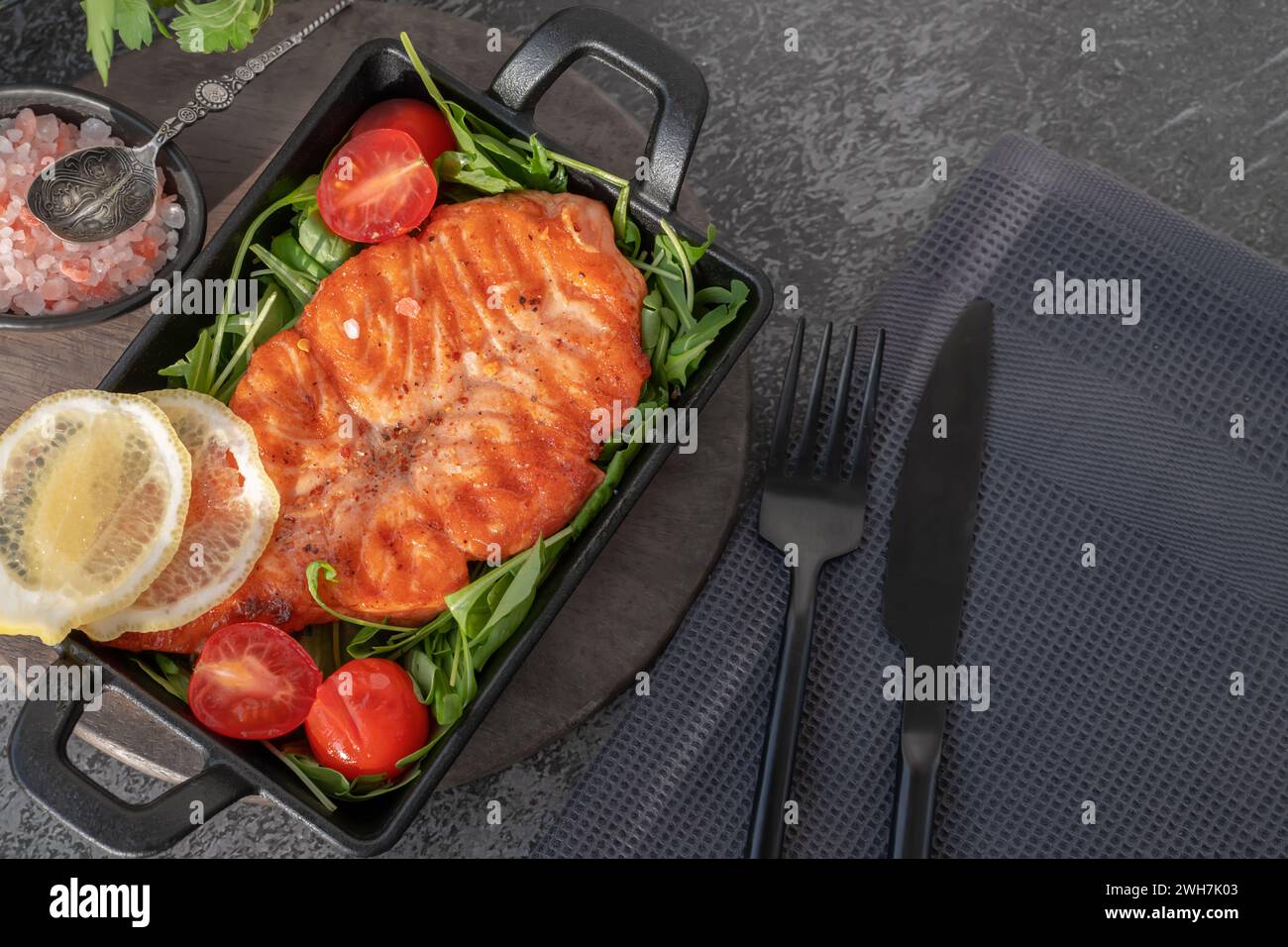 Grilled salmon steak with arugula salad, tomatoes and shallots. The concept of healthy eating, diet, low calorie. Stock Photo