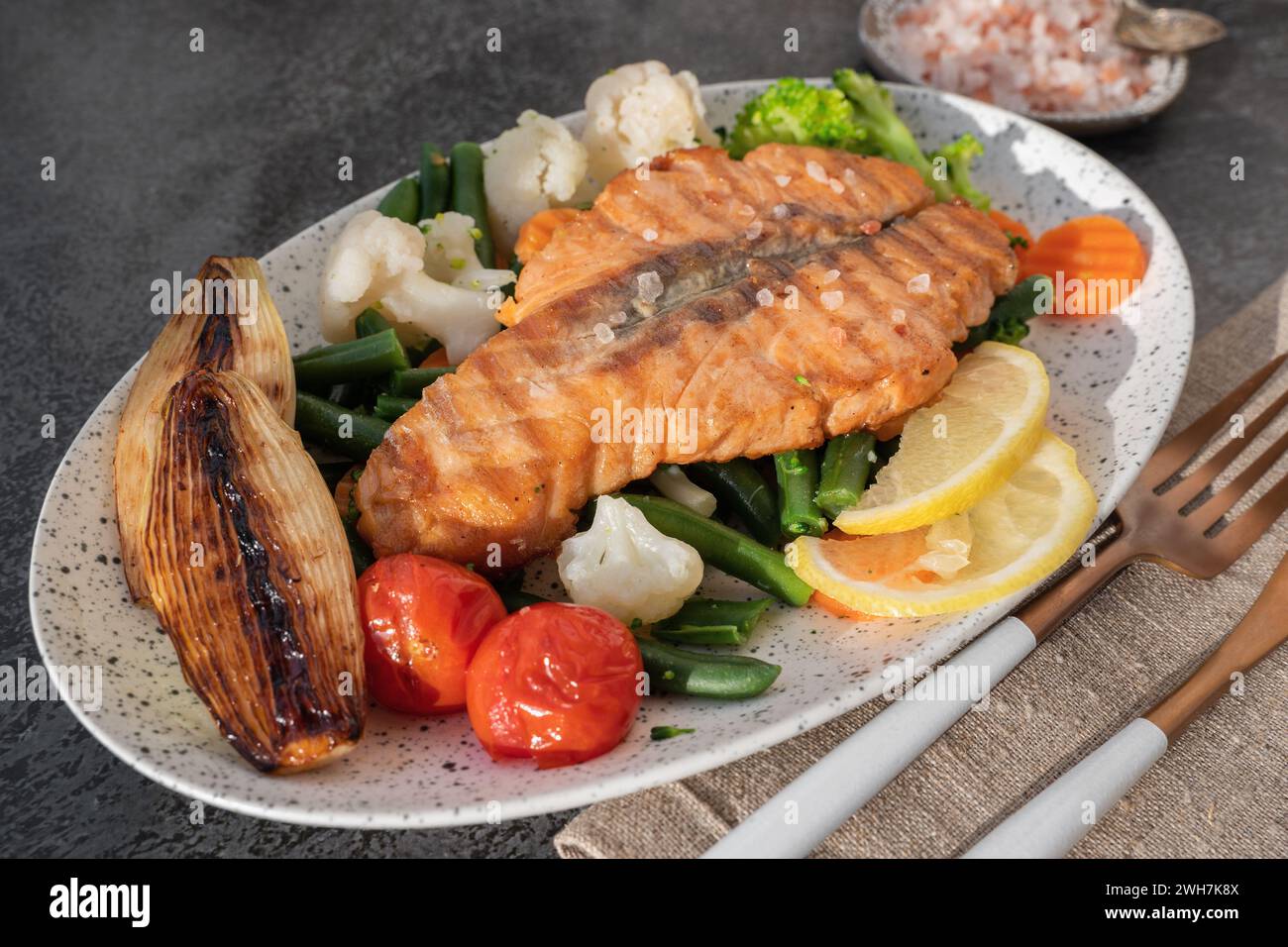 Grilled salmon steak with vegetables - cauliflower and broccoli, tomatoes and shallots. Healthy eating concept. Close-up Stock Photo