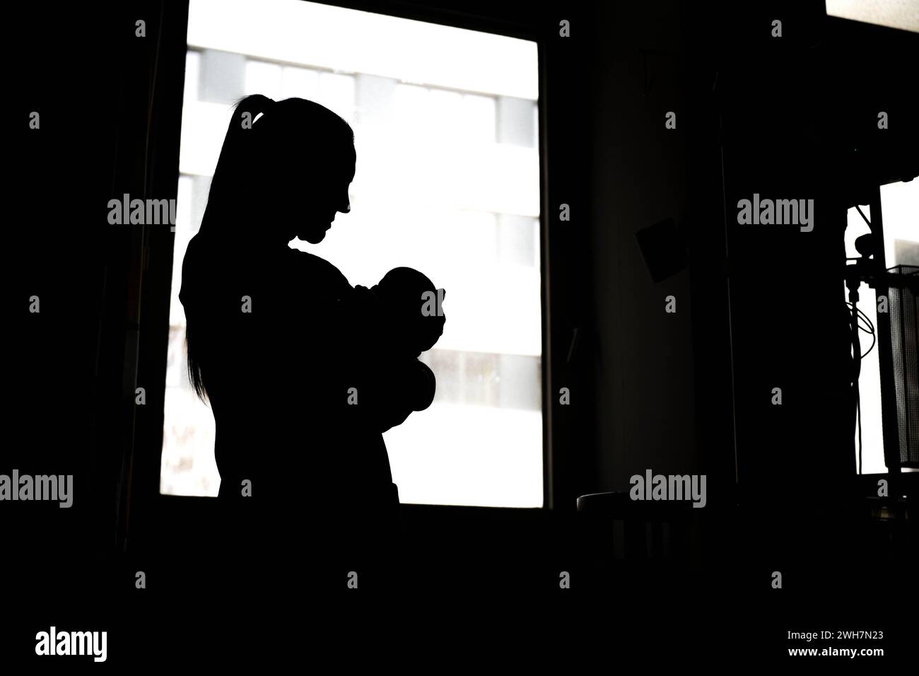 Bremen, Germany. 08th Feb, 2024. A woman stands with a newborn baby at the hospital window. Bremen wants to improve working conditions for nurses and midwives with a pilot project in a hospital. The 'I'm nursing again because.' project was launched at the beginning of February at the St. Joseph-Stift hospital in Bremen. Over the next four years, the aim is to work with nurses and midwives to improve working conditions in the delivery room and maternity ward. Credit: Sina Schuldt/dpa/Alamy Live News Stock Photo