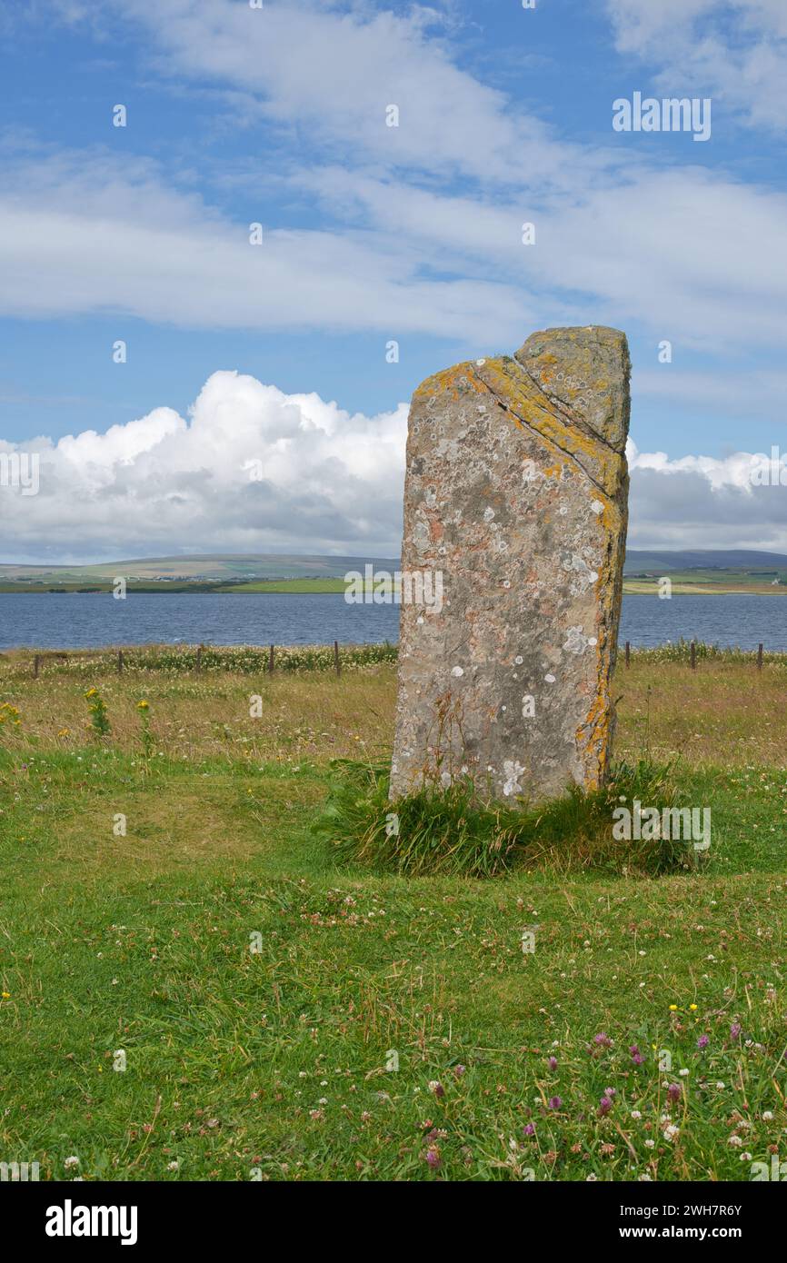 A historic standing stone on the Orkney Island with the sea and hills ...