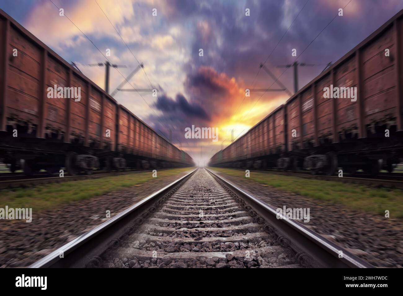 Railroad in motion with blur effect at sunset with dramatic sky. Train traveling on the railway. Stock Photo
