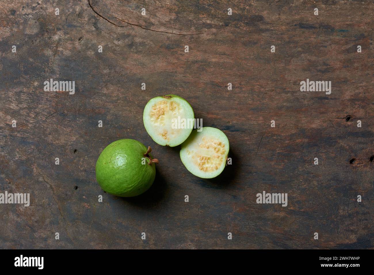 guava on wooden surface background, oval shaped common tropical and nutrient-rich fruit that is high in vitamin c, fiber and antioxidants Stock Photo