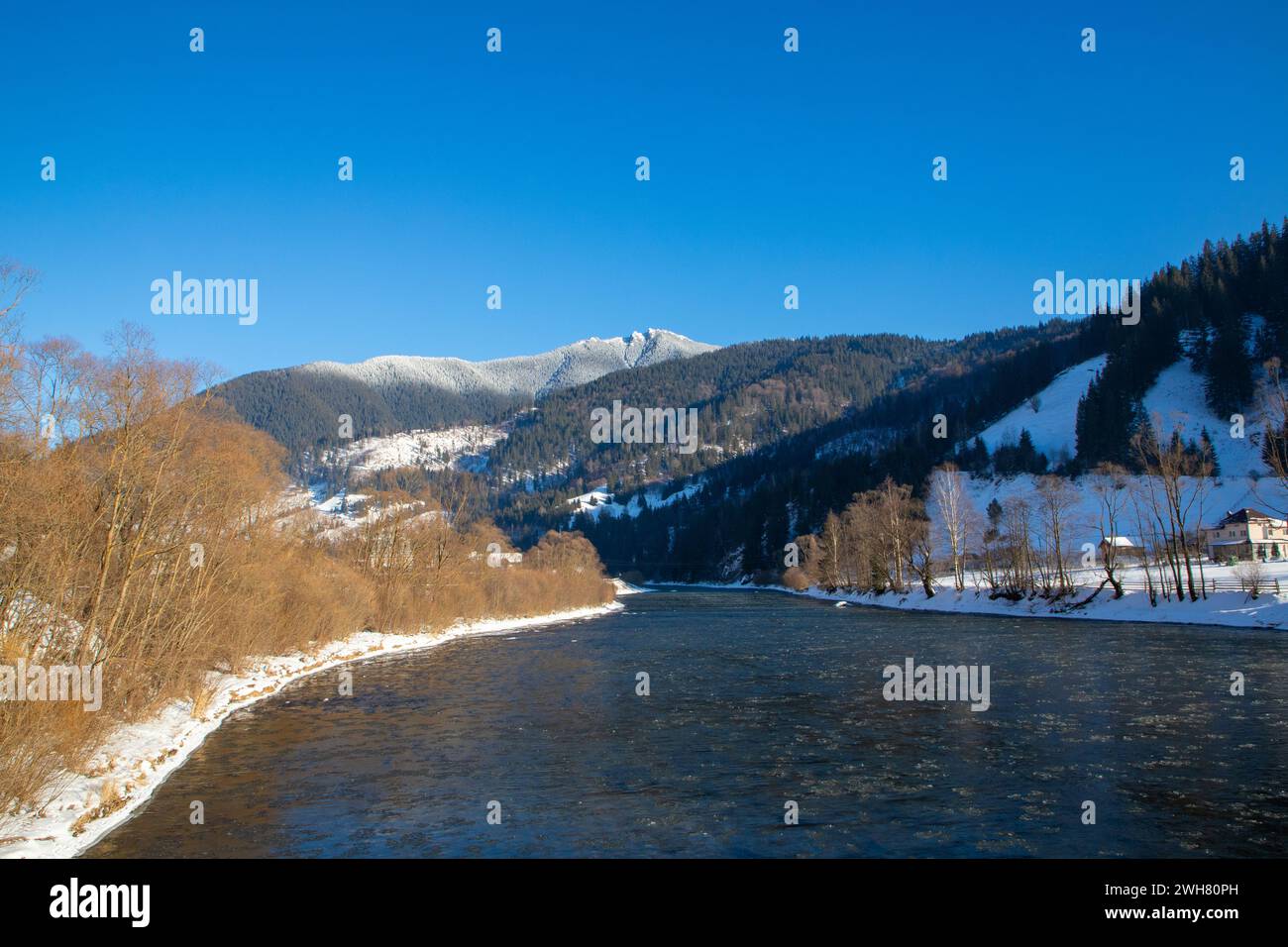 Snow-covered ground and river with a majestic mountain in the background Stock Photo